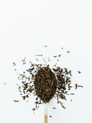 Medium black tea with red highlights fill the silver spoon and spill onto the white background
