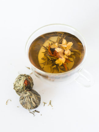 Red Lily and light yellow jasmine flowers center the green and white tea wrapped ball unfurls light gold in hot water