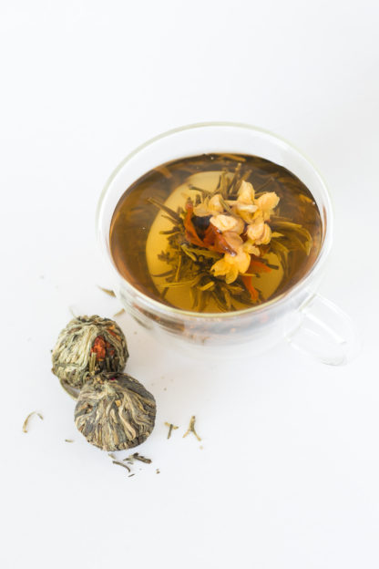 Red Lily and light yellow jasmine flowers center the green and white tea wrapped ball unfurls light gold in hot water