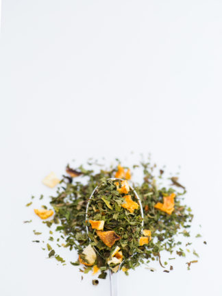 Bright chopped orange skin pieces blended with bright green chopped mint leaves spill over onto a white background