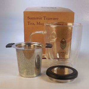Stainless steel infuser with insulated wings and lid bumper in front of the perfect double walled clear glass tea mug come together in a decorative box