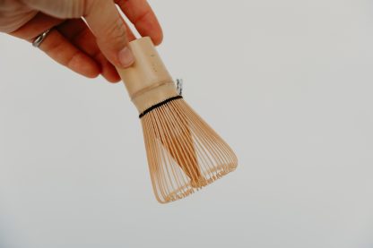 Hand holding a bamboo matcha whisk
